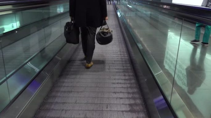 人们在机场的活动传送带上经过。人们赶往航班，在国际机场航站楼的人行道上行走自动扶梯