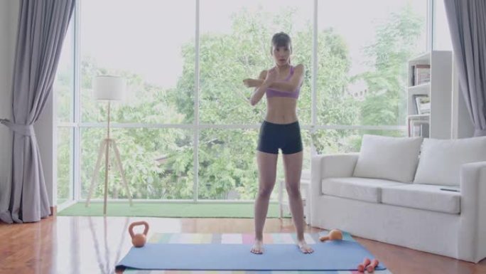 健身女人暖身，伸展手臂和肩膀，伸懒腰，站立。美丽的亚洲女人在体育。