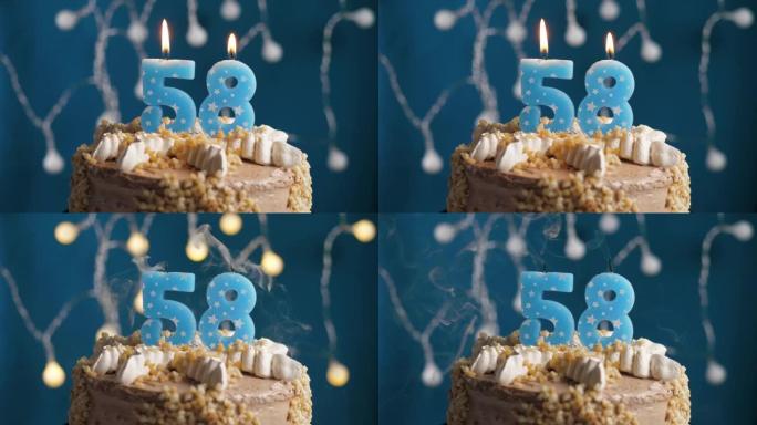 蓝色背景上有58号蜡烛的生日蛋糕。蜡烛吹灭了。慢动作和特写视图
