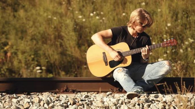 坐在铁轨上弹吉他的长发少年
