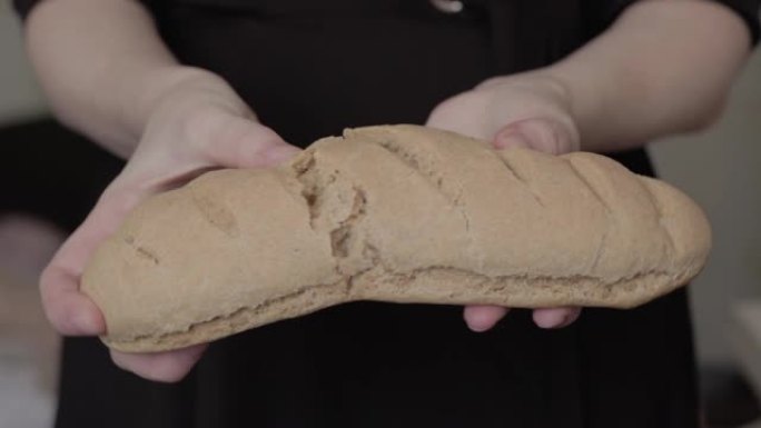 女性的手打碎了一个新鲜出炉的自制甜面包。女孩拿着玉米面面包。无麸质烘焙健康食品。分享食物，捐赠和对待