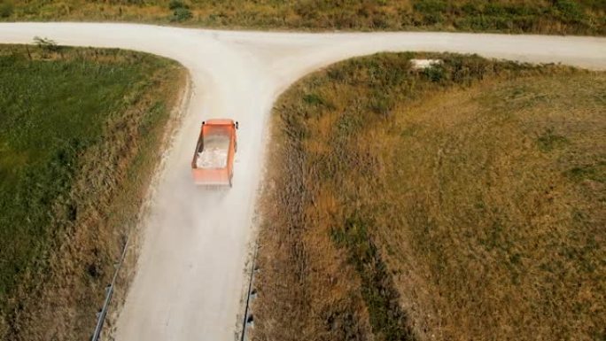 卡车的鸟瞰图。一辆自卸车，用卡车运送建筑碎屑石头和沙子，沿着乡间小路行驶。卡车运输物流货物交付