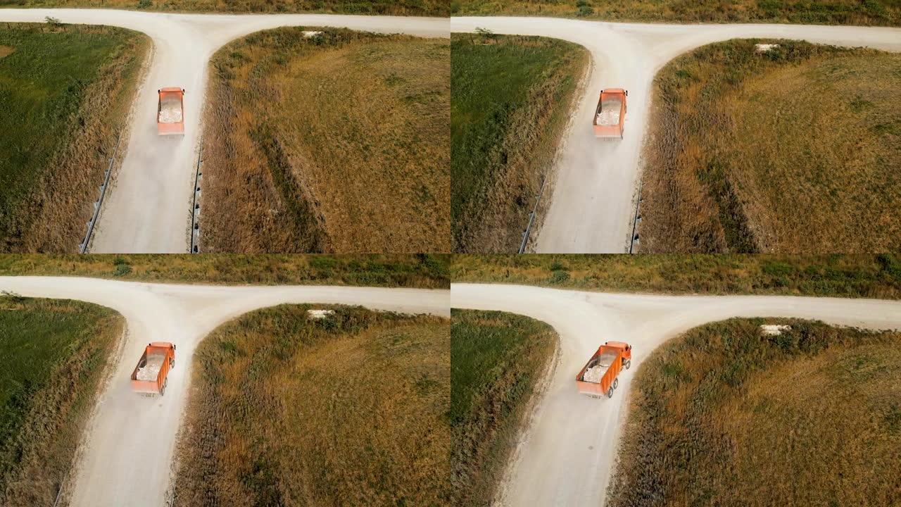 卡车的鸟瞰图。一辆自卸车，用卡车运送建筑碎屑石头和沙子，沿着乡间小路行驶。卡车运输物流货物交付