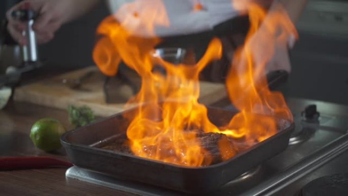 厨师在烤盘上制作flambe风格的牛排菲力牛排。用明火点燃石油和酒精。美食。美食厨房里的营养。做饭。
