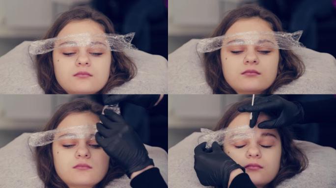 专业大师眉女在美容院中去除眉毛上的薄膜并去除眉毛上的液体