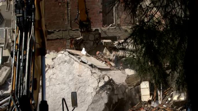液压破碎器和柱式切割机挖掘机后机在拆除旧公寓房屋中工作