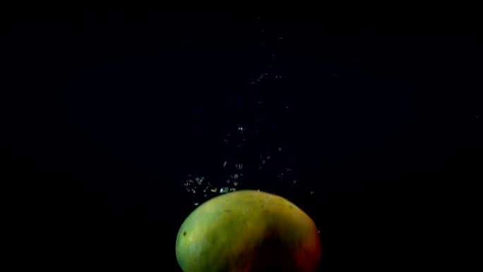 黑色背景下的水中掉落芒果的视频