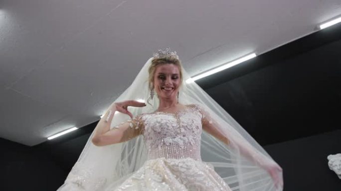 金发新娘身穿白色婚纱，头戴皇冠，在镜头前蒙上了面纱