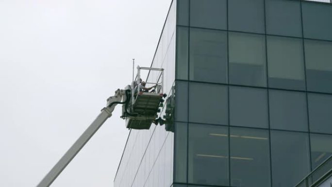 高空作业。蓝领工人团队使用升降平台检查办公楼玻璃立面。