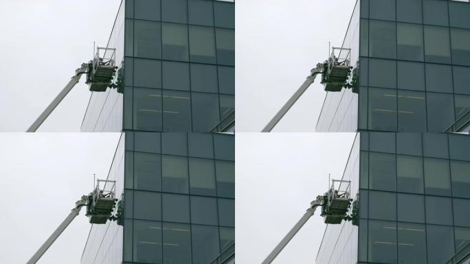 高空作业。蓝领工人团队使用升降平台检查办公楼玻璃立面。
