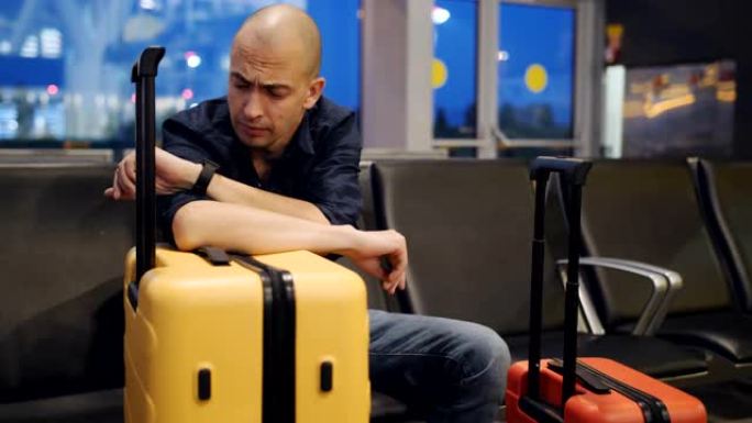 疲惫的男子在机场等飞机时打哈欠并入睡