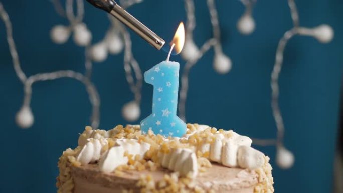 蓝色背景上有1个数字蜡烛的生日蛋糕。蜡烛着火了。慢动作和特写视图