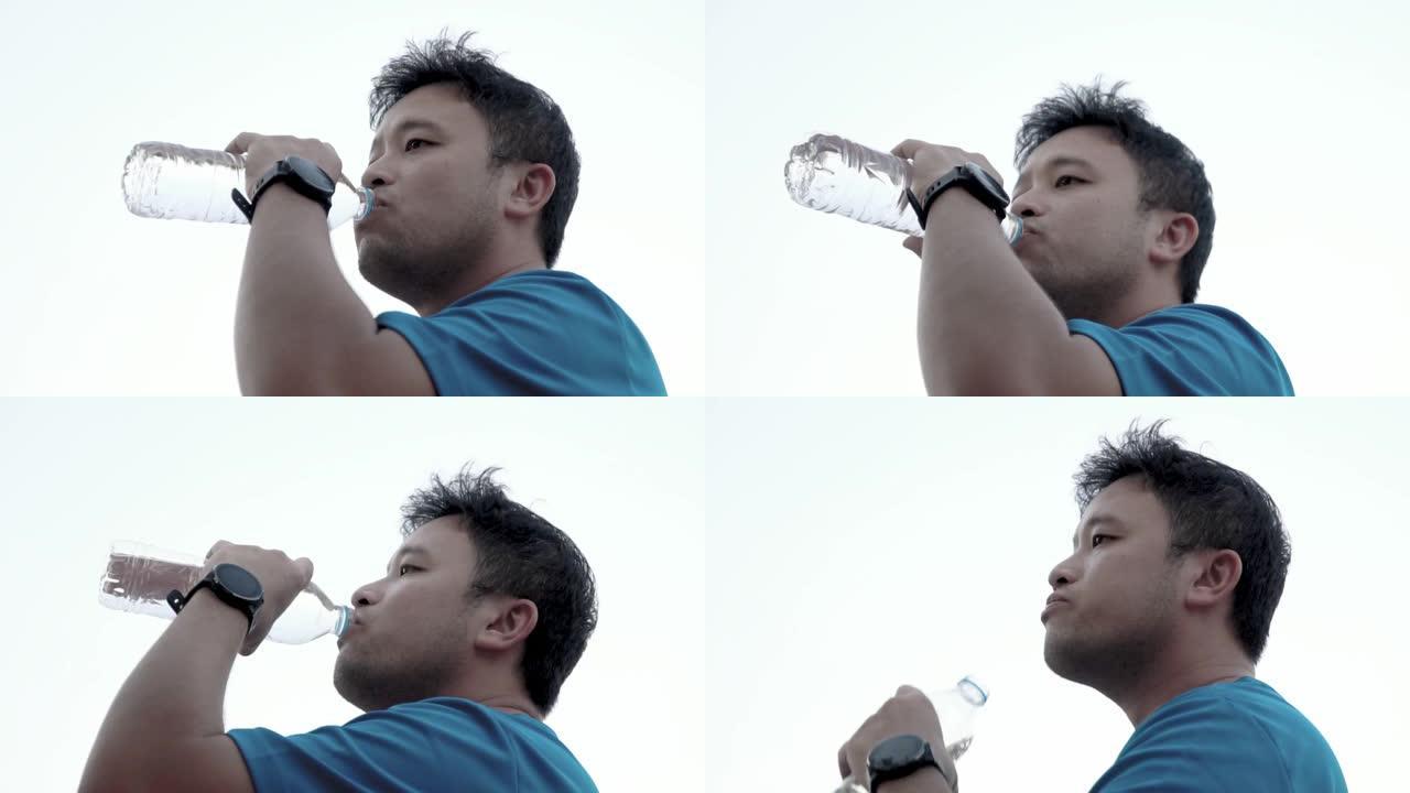 男子跑步后喝水。喝矿泉水的男人饮用水源