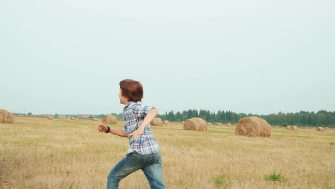 少年男孩在草堆背景下的农田上奔跑。少女坐在村庄收割田上的干草堆上。青少年朋友在乡村球场玩得开心。