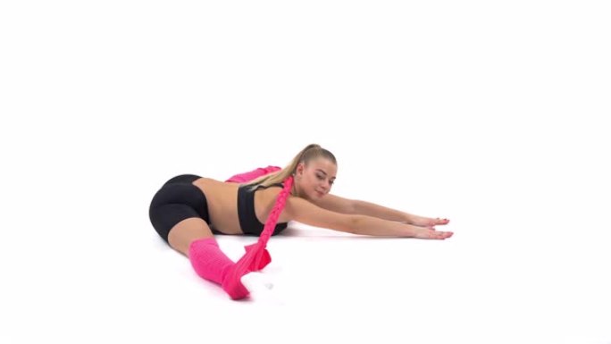 一位年轻的职业女运动员使用弹性绳进行伸展运动的侧视图 (在脚跟伸展位置向前倾斜)。孤立，在白色背景上