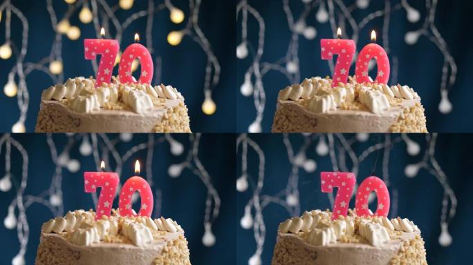 蓝色背景上有70号粉色蜡烛的生日蛋糕。蜡烛吹灭了。慢动作和特写视图