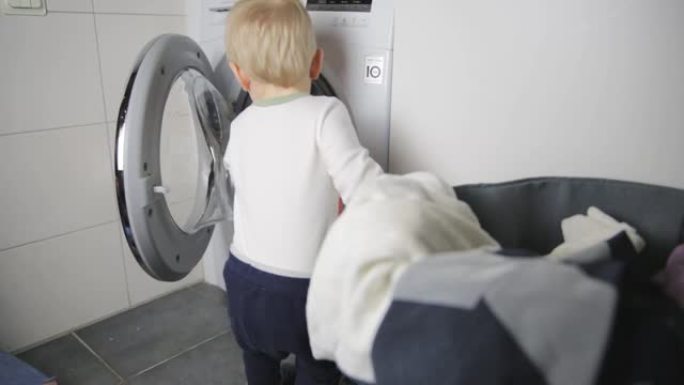 两岁的孩子做家务。装载洗衣机。