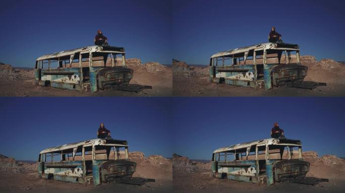 坐在阿塔卡马沙漠废弃巴士屋顶上的女人