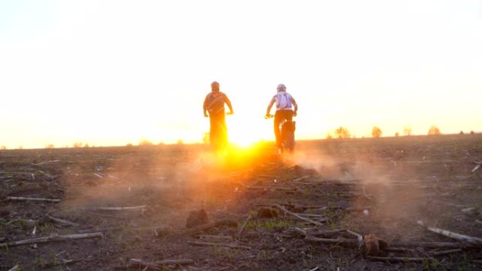 骑摩托车的人站在摩托车上骑到日落。朋友们在黄昏时积极休息户外驾驶强大的摩托车。骑自行车的人一起享受旅