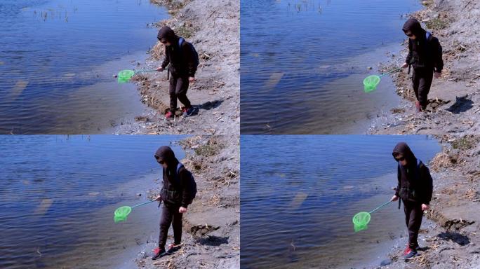 男孩正在用蝴蝶网在河上撒播青蛙和鱼。