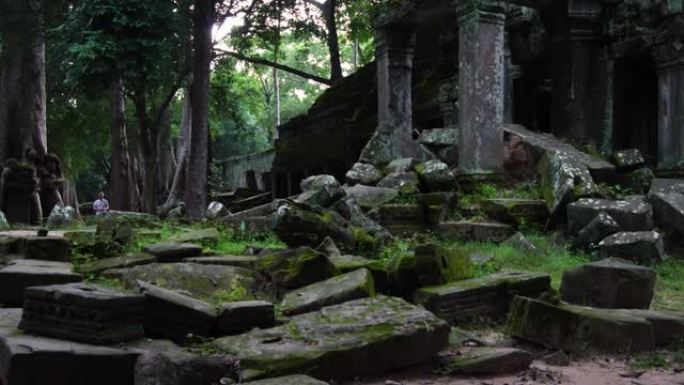 在吴哥窟寺庙废墟中行走的游客。树木生长在建筑物中。联合国教科文组织历史遗址。著名的旅游目的地为背包客