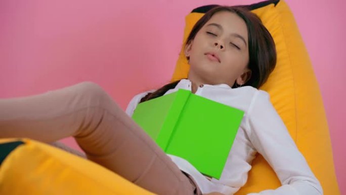 孩子睡在豆袋椅上的书孤立在粉红色