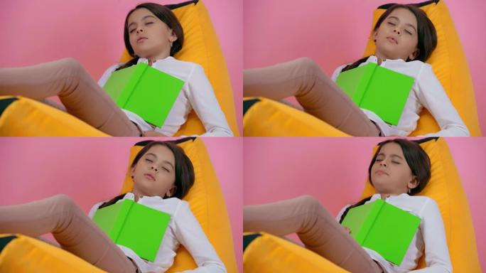 孩子睡在豆袋椅上的书孤立在粉红色