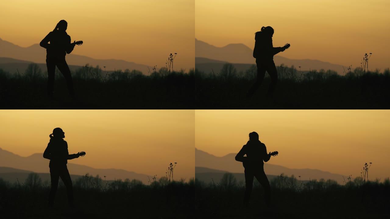一个年轻的女人带着吉他在日落时在大自然中演奏音乐。轮廓。