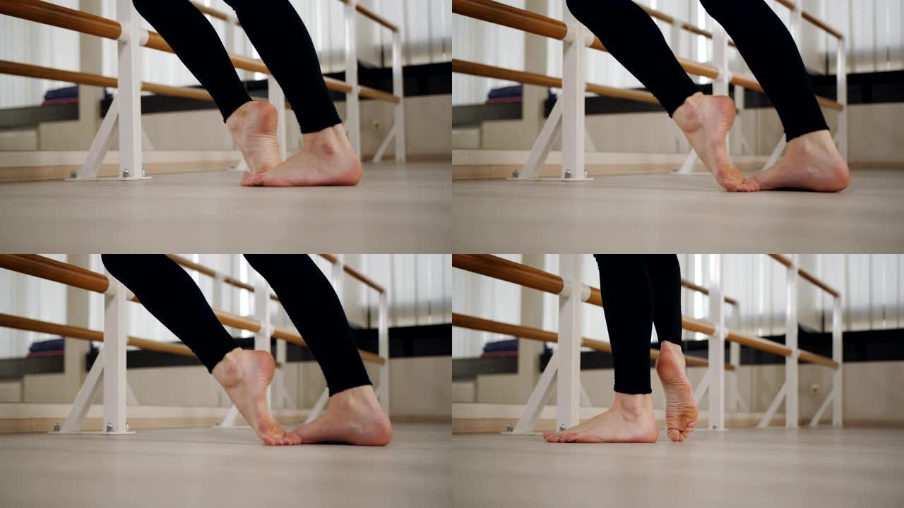 女舞者在芭蕾舞酒吧的舞厅里热身。脚的特写。