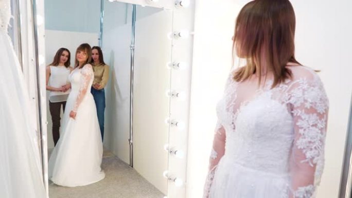 新娘在婚纱上的镜子反射，沙龙旁有和蔼可亲的朋友