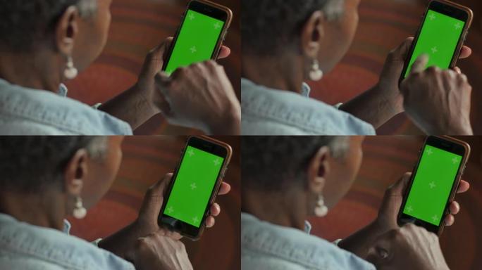 非裔美国妇女在绿屏手机上上下滚动