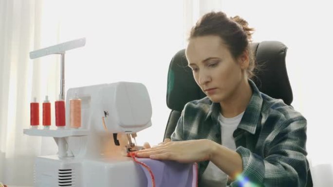 一个年轻女子用缝纫机缝制紫罗兰织物的肖像。女人的手缝了一件衣服。时尚、创作和剪裁