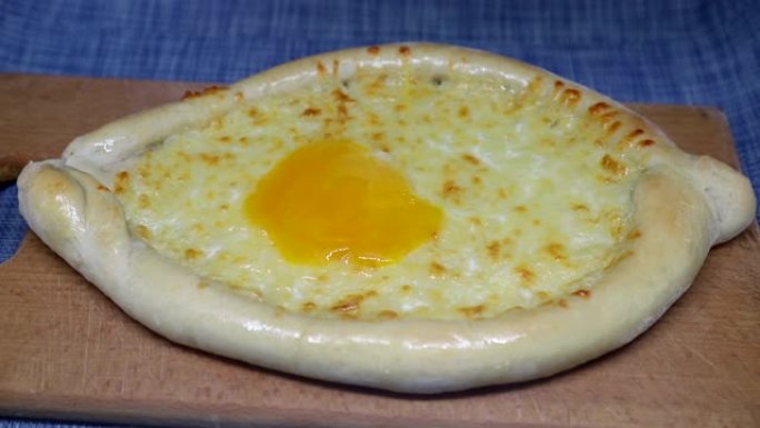 将鸡蛋倒在khachapuri (格鲁吉亚奶酪糕点) 上