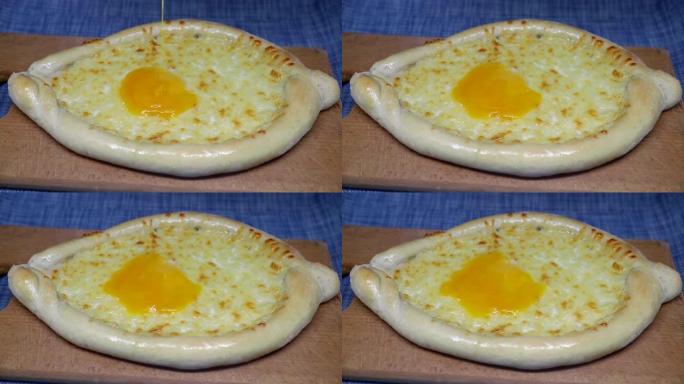 将鸡蛋倒在khachapuri (格鲁吉亚奶酪糕点) 上