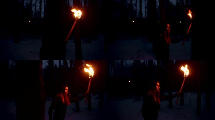 年轻的失散女子带着火把晚上在冬季森林里散步寻找出路