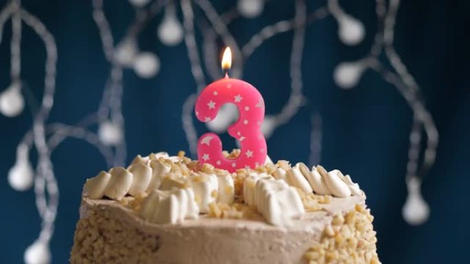蓝色背景上有3个数字粉色蜡烛的生日蛋糕。蜡烛吹灭了。慢动作和特写视图