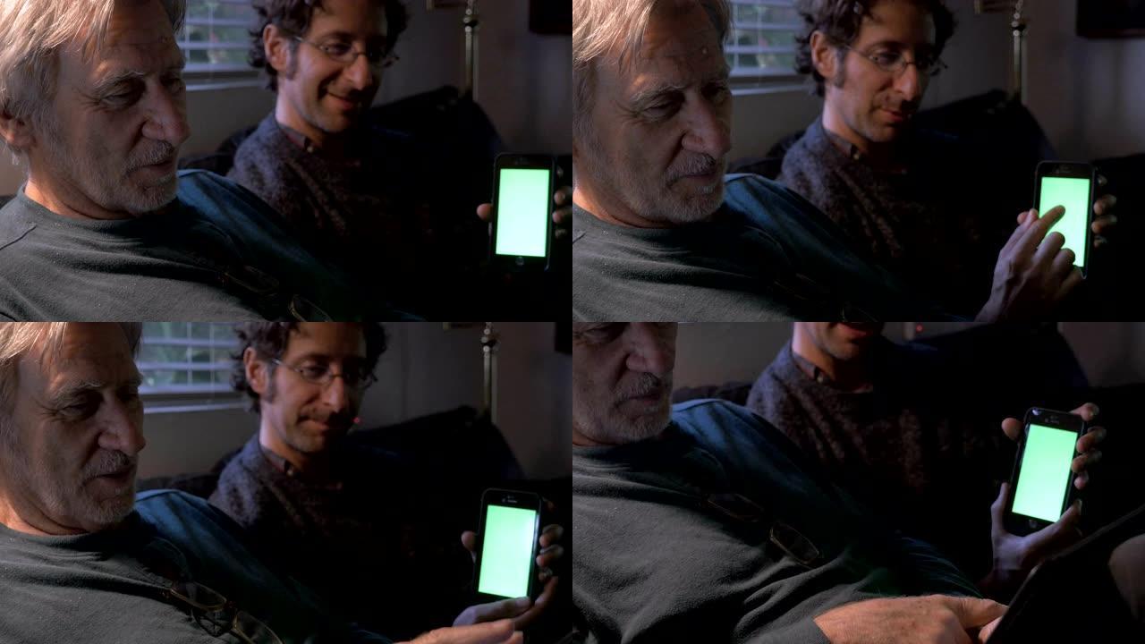 一位上了年纪的父亲正在操作平板电脑，而他的小儿子正在向他展示自己的手机