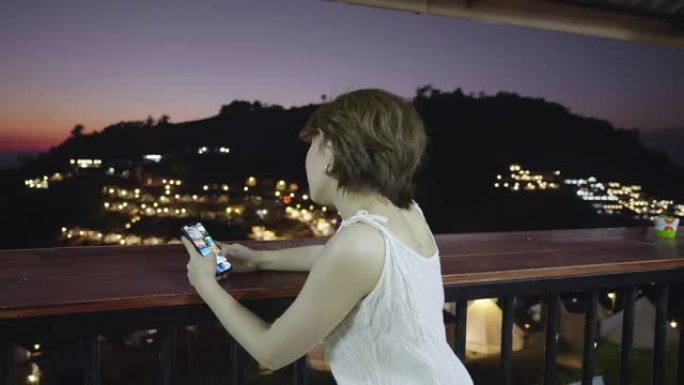 年轻的亚洲妇女旅行放松并在晚上使用智能手机