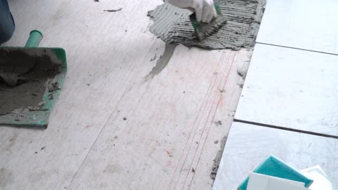 4k亚洲高级杂工用抹子用水泥铺砖地板。高级技术员修理建筑工程或瓷砖房间地板的家庭装修。资深老人diy