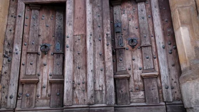在古代中世纪天主教堂中关闭两扇带有金属把手的旧木门的特写镜头。