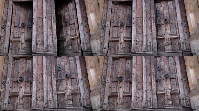 在古代中世纪天主教堂中关闭两扇带有金属把手的旧木门的特写镜头。