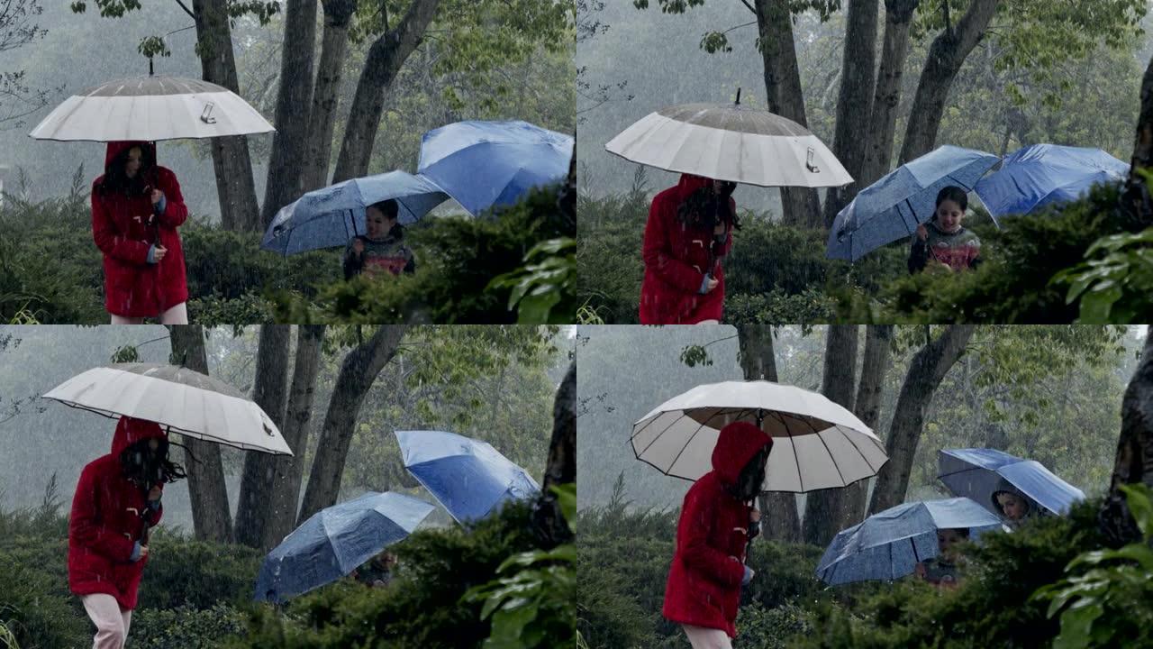 三个孩子的慢动作在雨中快乐奔跑，用雨伞的水坑