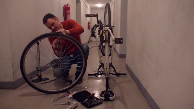 一位父亲正在车库里修理一辆儿子自行车的车轮。