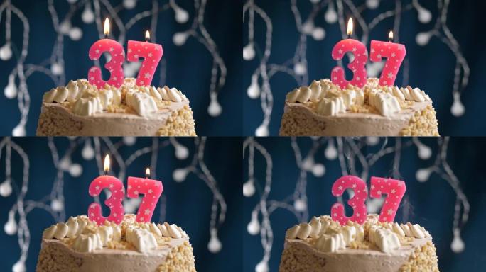 蓝色背景上有37个粉色蜡烛的生日蛋糕。蜡烛吹灭了。慢动作和特写视图