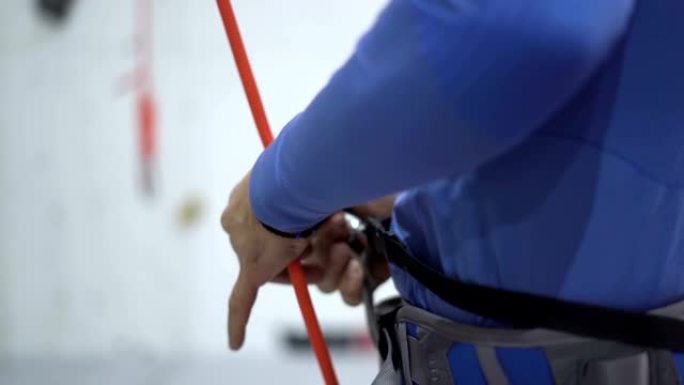 带绳索的登山者设置设备准备在室内攀岩墙上练习