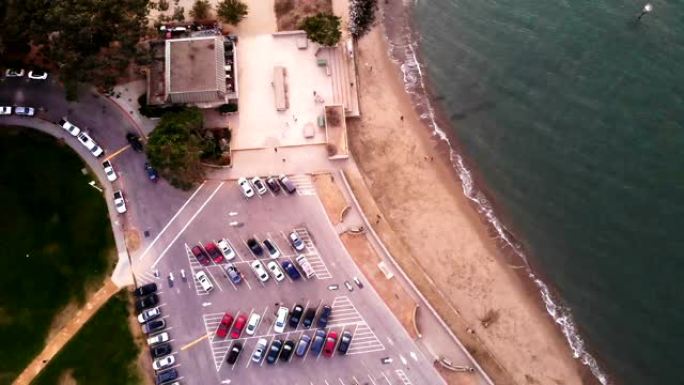 粉红日落沙滩和棕榈树附近海洋停车场的鸟瞰图。