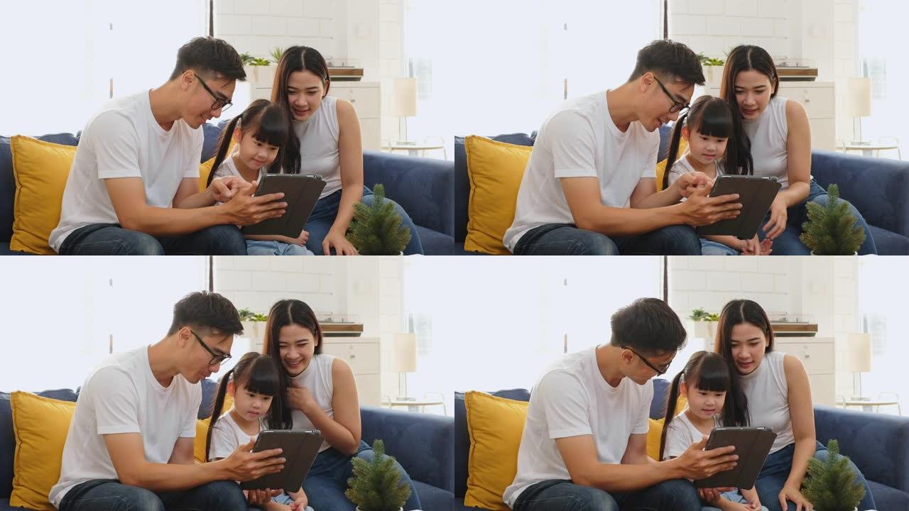 快乐的亚洲家庭在沙发/家庭游戏、教育平板电脑上共度时光