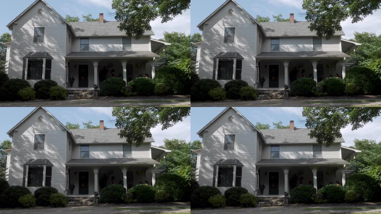 在夏天建立一个两层灰色房屋的照片，该房屋带有木质壁板