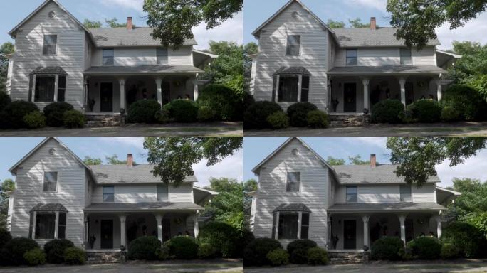 在夏天建立一个两层灰色房屋的照片，该房屋带有木质壁板