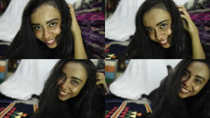 美丽的中东女孩笑着躺在家里的床上看着相机